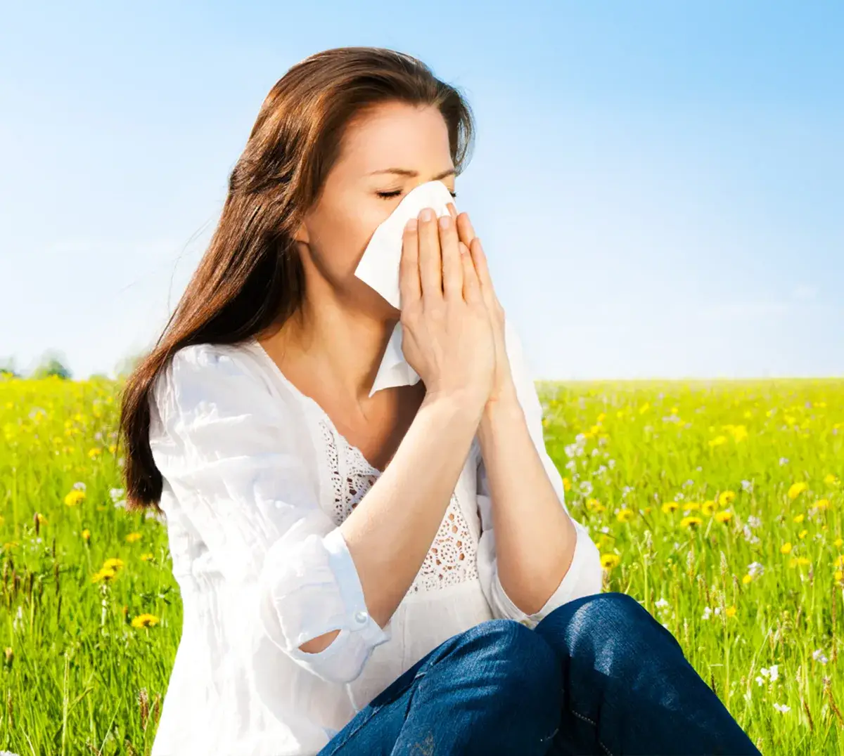Allergische Reaktion de Nasenschleimhaut Ein Frau auf einer Wiese putzt sich die Nase
